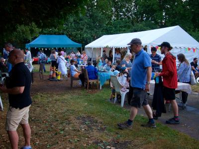 a communal space on the allotment with a marquee and gazebo and people around